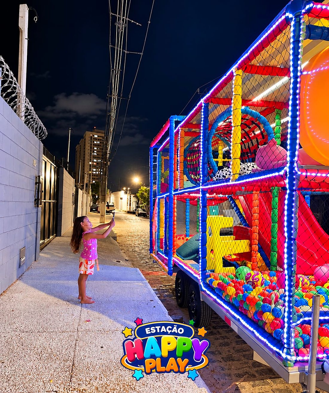 Menina fotografando a Carreta Kids iluminada da Estação Happy Play